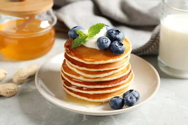 Plate of tasty pancakes with blueberries, sauce and mint on grey marble table — Stock Photo, Image