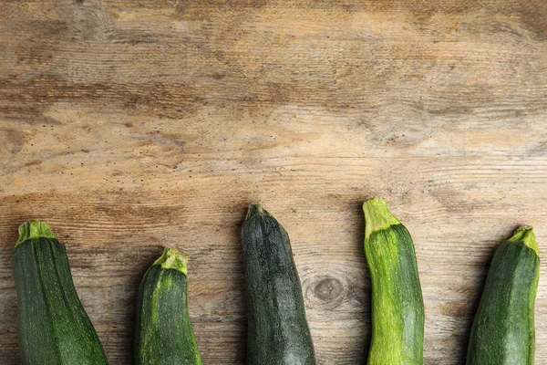 Fresh ripe green zucchini on wooden background, flat lay. Space for text