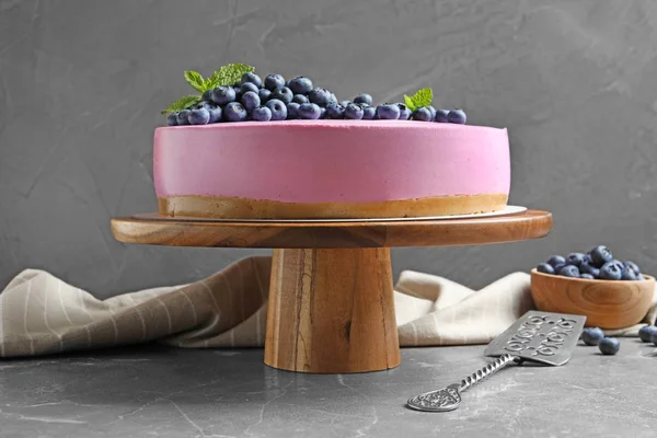 Holzständer mit leckerem Blaubeerkuchen auf grauem Tisch — Stockfoto