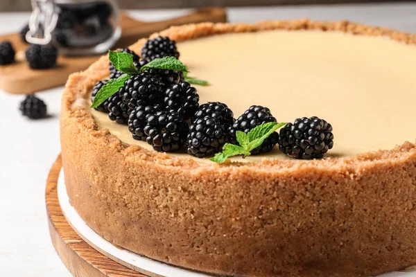 Delicious cheesecake decorated with blackberries on table