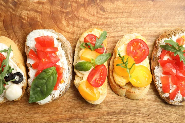 Deliziose bruschette di pomodoro su sfondo di legno, posa piatta — Foto Stock