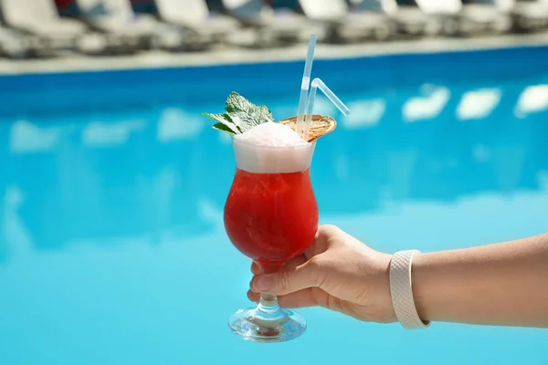 Femme avec cocktail rafraîchissant près de la piscine en plein air, gros plan — Photo