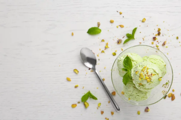 Délicieuse glace verte servie dans un bol à dessert sur une table en bois blanc, vue sur le dessus. Espace pour le texte — Photo