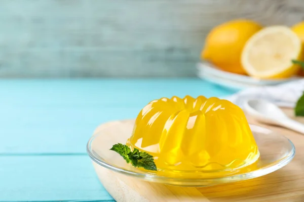Вкусное желтое желе с мятой на светло-голубом деревянном столе — стоковое фото