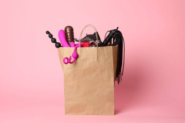 Pembe arka planda farklı seks oyuncakları ile Kağıt alışveriş çantası