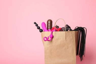 Pembe arka planda farklı seks oyuncakları ile Kağıt alışveriş çantası. Metin için alan