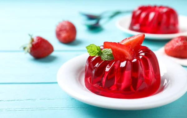 Délicieuse gelée rouge aux fraises et menthe sur table en bois bleu clair — Photo