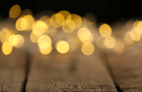 Yellow Christmas lights on wooden table, blurred view