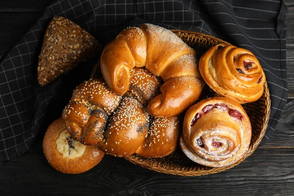 Different delicious fresh pastries on dark wooden background, flat lay — Stock Photo, Image