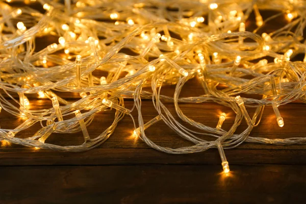 Hermosas luces brillantes de Navidad sobre fondo de madera — Foto de Stock