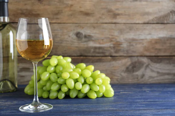 Uvas jugosas frescas maduras y vino sobre mesa azul sobre fondo de madera. Espacio para texto — Foto de Stock