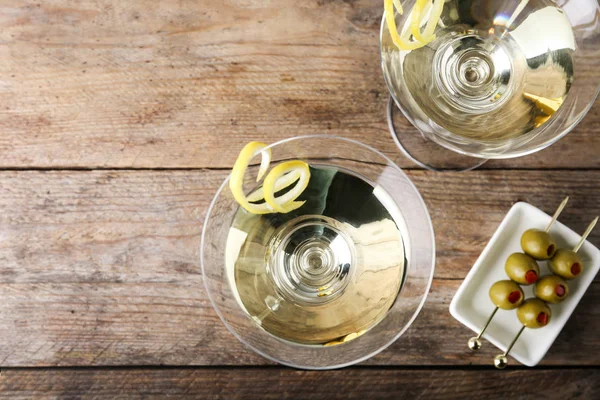 Glasses of lemon drop martini cocktail with zest on wooden table, flat lay — Stock Photo, Image