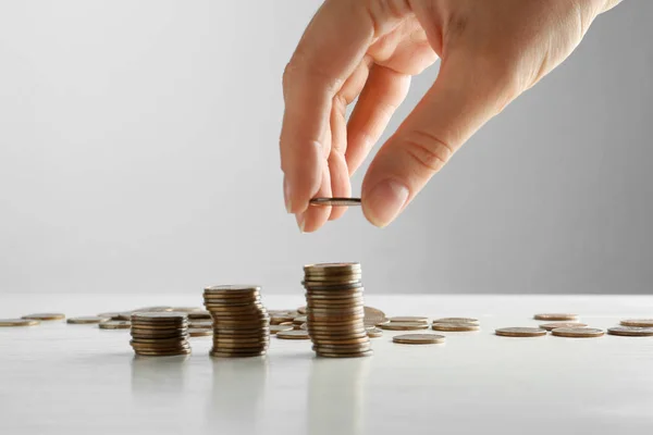 Woman stacking coins on white wooden table, closeup — Stock Photo, Image