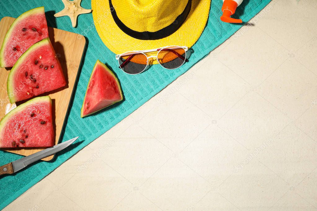 Flat lay composition with beach accessories and watermelon on sand, space for text