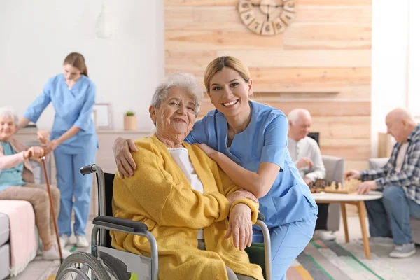 Infirmière avec une femme âgée en fauteuil roulant à la maison de retraite. Aider les personnes âgées — Photo