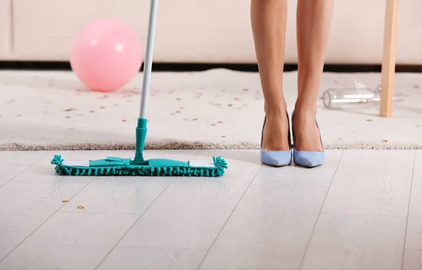 Женщина со шваброй убирать грязную комнату после вечеринки, крупным планом вид ног — стоковое фото
