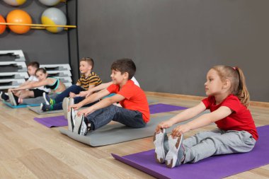 Sevimli küçük çocuklar katta oturan ve okul spor salonunda fiziksel egzersiz yapıyor. Sağlıklı yaşam tarzı