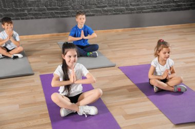Sevimli küçük çocuklar katta oturan ve okul spor salonunda fiziksel egzersiz yapıyor. Sağlıklı yaşam tarzı