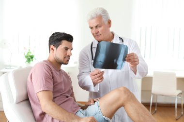 X-ışını ve klinikte genç bir hasta ile kıdemli doktor. Diz sorunu