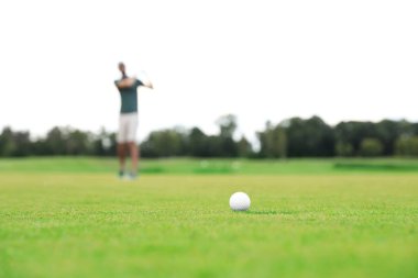 Yeşil sahada golf oynayan adam, top odakta. Spor ve eğlence