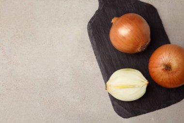 Gri masa üzerinde olgun soğan ile Kayrak tahtası, üst görünümü. Metin için alan