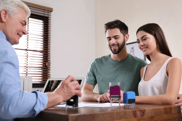 Notaire principal travaillant avec un jeune couple au bureau — Photo