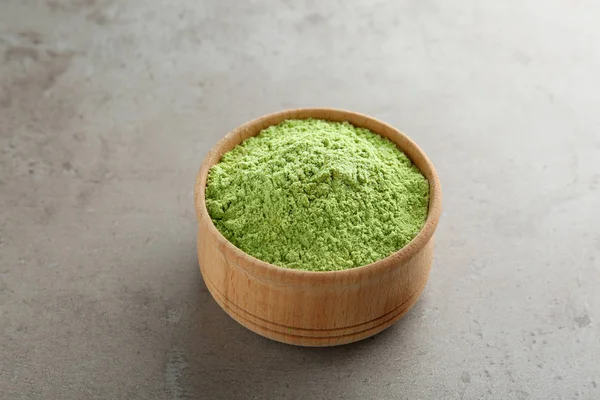 Bowl of wheat grass powder on grey table