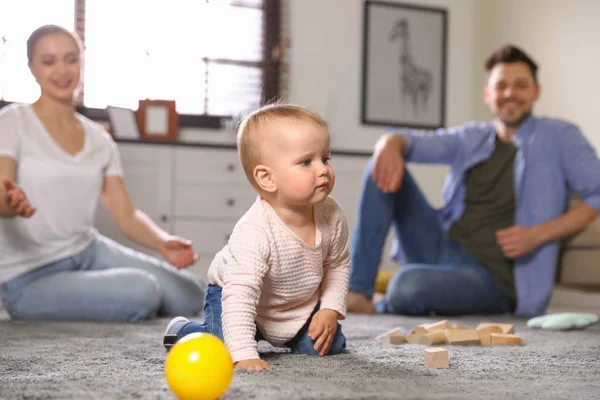 Родители смотрят, как их ребенок ползает по полу дома — стоковое фото