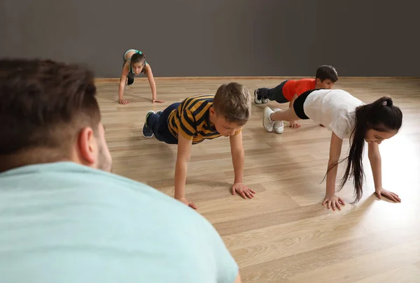 Lindos niños pequeños y entrenador haciendo ejercicio físico en el gimnasio de la escuela. Estilo de vida saludable —  Fotos de Stock