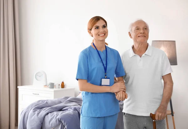 Медсестра в форме помогает пожилой женщине в помещении. Пространство для текста — стоковое фото