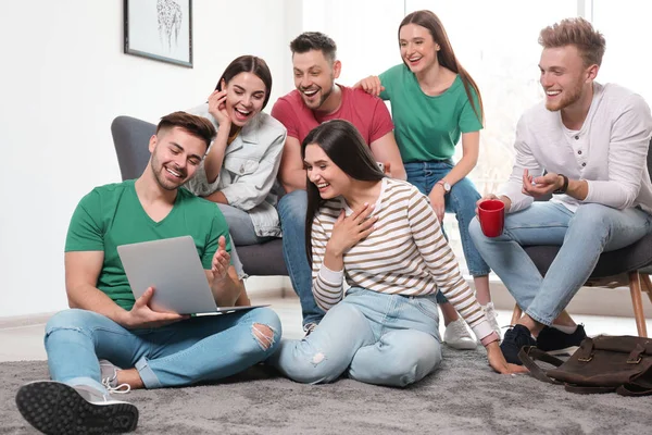 Grupa szczęśliwych ludzi z laptopem w salonie — Zdjęcie stockowe