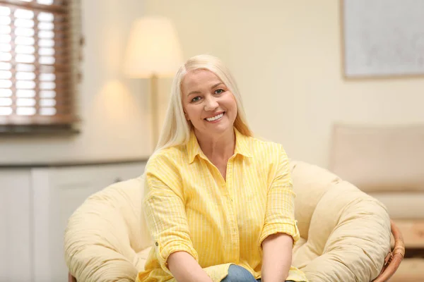 Retrato de mulher madura feliz sentada na cadeira papasan em casa — Fotografia de Stock