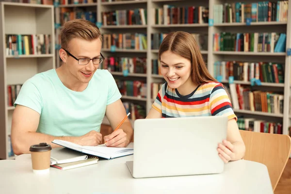 Jóvenes discutiendo proyecto de grupo en la mesa de la biblioteca —  Fotos de Stock