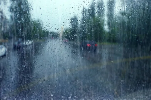 Vista borrosa de la calle de la ciudad a través de una ventana húmeda en el día lluvioso — Foto de Stock