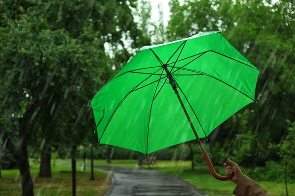 Kobieta z zielonym parasolem w parku w deszczowy dzień — Zdjęcie stockowe
