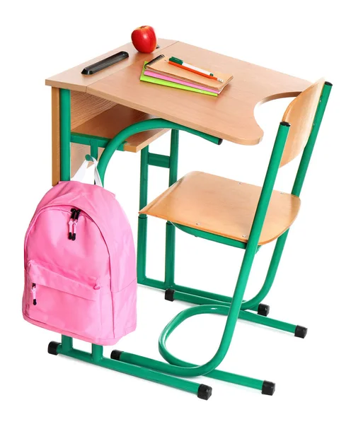 Деревянный школьный стол с канцелярскими принадлежностями, рюкзак и яблоко на белом фоне — стоковое фото