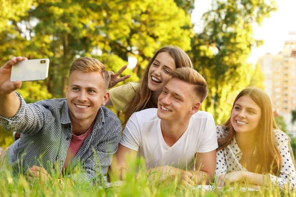 Unga människor tar Selfie samtidigt ha picknick i parken på sommardagen — Stockfoto