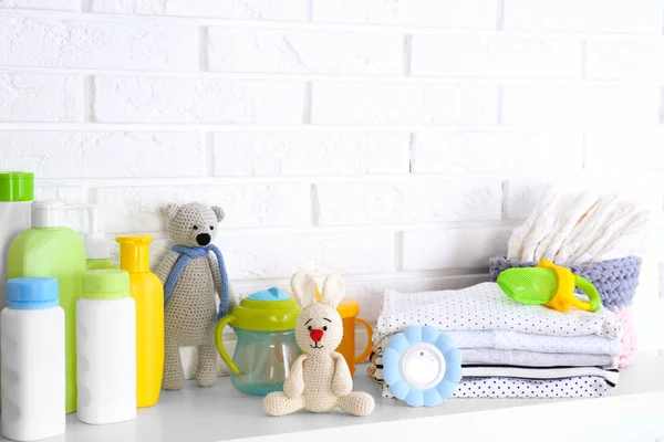 Baby accessoires op plank in de buurt van witte bakstenen muur. Ruimte voor tekst — Stockfoto