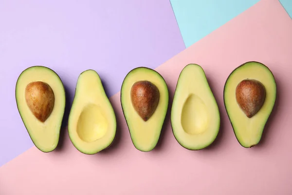 Cut fresh ripe avocados on color background, flat lay — Stock Photo, Image