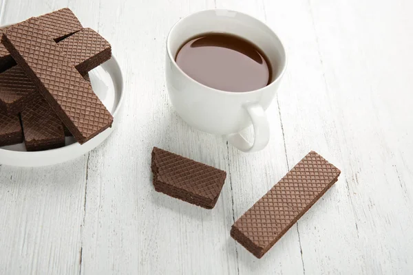 Prato de deliciosas bolachas de chocolate com xícara de chá em fundo de madeira branca — Fotografia de Stock