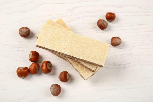 Deliciosas obleas con avellanas sobre fondo de madera blanca — Foto de Stock