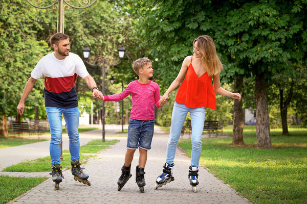 Young happy family roller skating in summer park