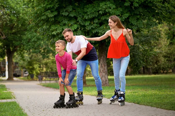 Giovane famiglia felice pattinaggio a rotelle nel parco estivo — Foto Stock