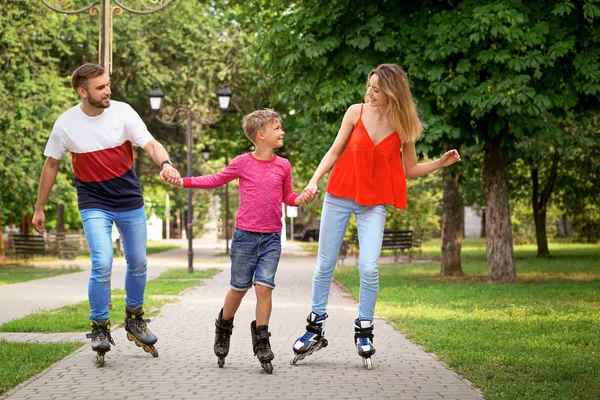 Giovane famiglia felice pattinaggio a rotelle nel parco estivo — Foto Stock