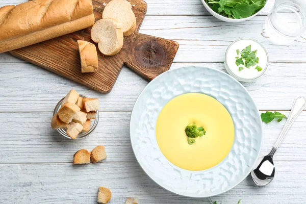 Tigela de sopa de creme de queijo com brócolis servido em mesa de madeira branca, flat lay — Fotografia de Stock