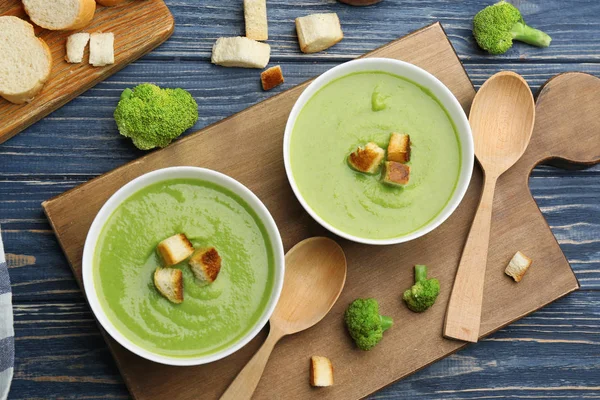 Platte lay samenstelling met kommen van broccoli crème soep op blauwe houten tafel — Stockfoto
