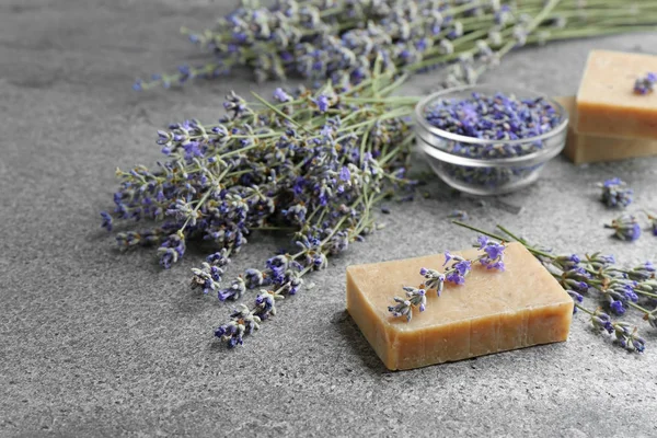 Barra de sabão feita à mão com flores de lavanda na mesa de pedra cinza, espaço para texto — Fotografia de Stock