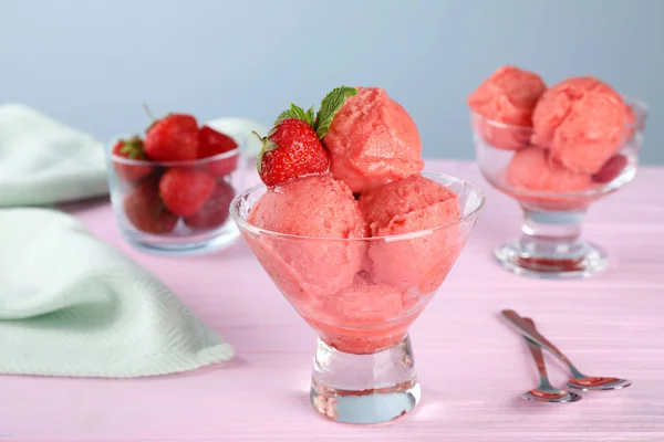 Lahodná jahodová zmrzlina v cukrářské misce podávané na růžovém dřevěném stole — Stock fotografie