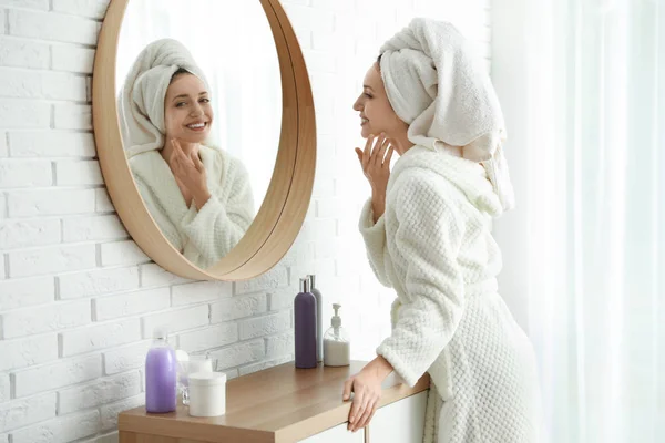 Bella giovane donna con asciugamano sulla testa vicino specchio all'interno — Foto Stock