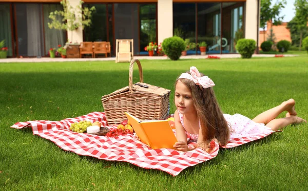 Gadis kecil yang lucu membaca buku di luar ruangan. Istirahat musim panas — Stok Foto